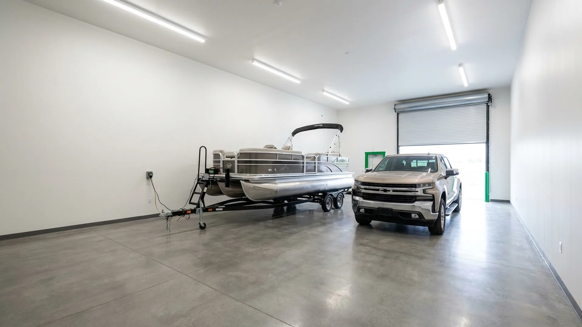 Pontoon boat and pickup truck parked in a wide indoor Due North storage unit with electrical outlet
